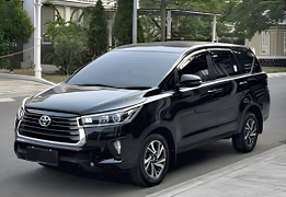 Toyota Kijang Innova warna abu-abu gelap (dark grey metallic) difoto dari sudut depan samping, menampilkan grille krom besar khas Innova, headlamp LED tajam, dan velg alloy premium. Sebagai salah satu unit armada sewa mobil di Medan, Innova ini menjadi pilihan populer untuk perjalanan bisnis, keluarga besar, maupun wisata ke Berastagi dan Danau Toba karena kenyamanan kabin dan performa mesin yang tangguh untuk medan menanjak.