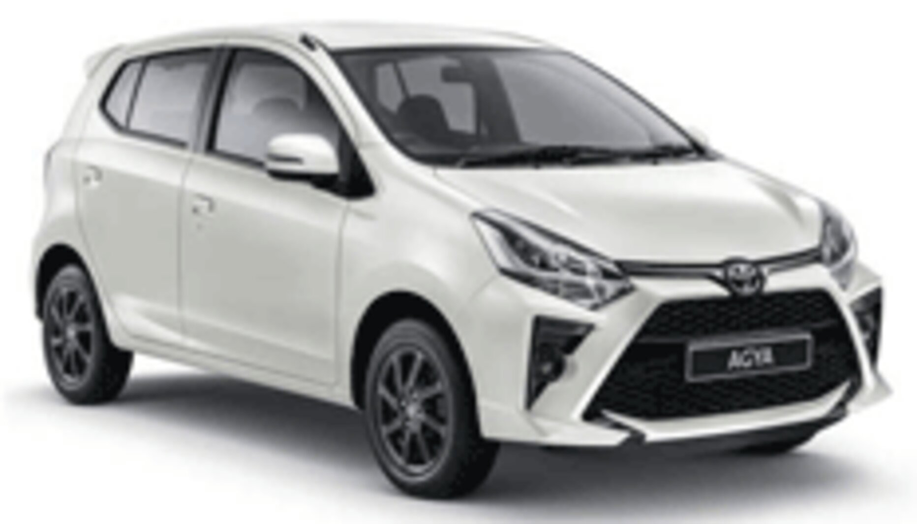 Toyota Agya GR Sport warna putih difoto dari sudut depan samping, menampilkan desain city car terbaru dengan grille depan trapesium tajam ala GR Sport, headlamp LED sipit modern, dan velg alloy hitam sporty. Sebagai armada ekonomis sewa mobil di Medan, Agya menjadi pilihan tepat untuk perjalanan dalam kota, solo traveler, pasangan, atau keluarga kecil yang mengutamakan efisiensi bahan bakar dan kemudahan parkir di area padat seperti pusat kota Medan.