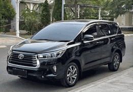 Toyota Kijang Innova warna abu-abu gelap (dark grey metallic) difoto dari sudut depan samping, menampilkan grille krom besar khas Innova, headlamp LED tajam, dan velg alloy premium. Sebagai salah satu unit armada sewa mobil di Medan, Innova ini menjadi pilihan populer untuk perjalanan bisnis, keluarga besar, maupun wisata ke Berastagi dan Danau Toba karena kenyamanan kabin dan performa mesin yang tangguh untuk medan menanjak.